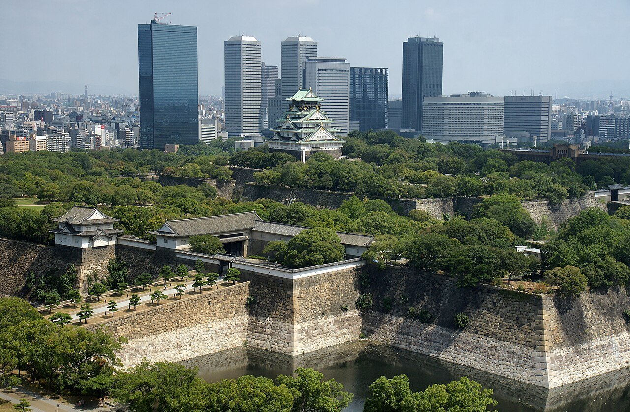 Osaka Castle's stone walls and moat, with the modern Osaka Business Park towers behind